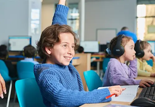 A child raising their hand to ask a question during their Explore Learning maths and English tuition session