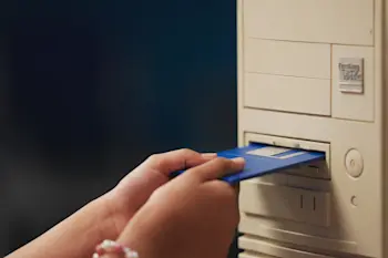 Someone inserting a floppy disc into a PC