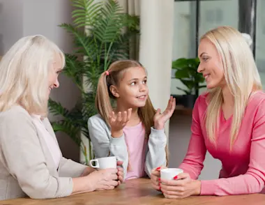 A mum and daughter chat with her grandmother at a kitchen table.