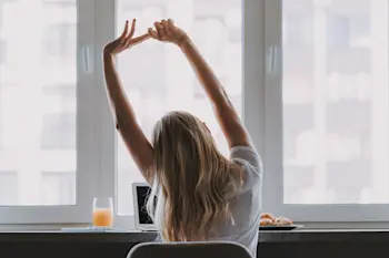 Child stretching at their computer with breakfast