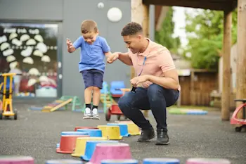 Mentor helping a child play in the playground