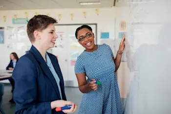 Teenager and a teacher working on a whiteboard together