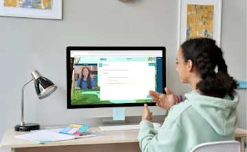 A teenage girl is working on a computer at a desk - on screen there is an Explore Learning tutor with an example question. 