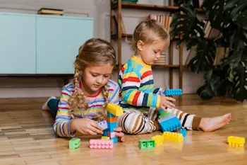 A young boy and girl playing with LEGO indoors