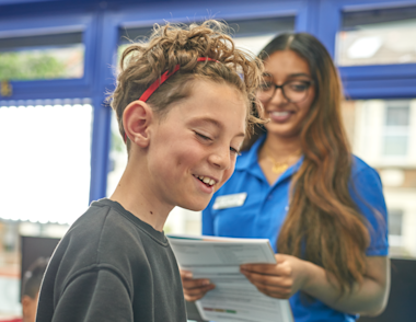 A child working on a problem with a tutor in the background