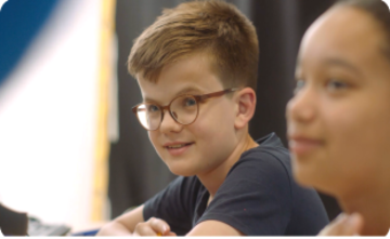 A child at an Explore Learning centre listens intently to his tutor (outside of shot).