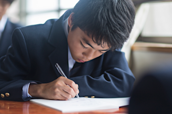 Child writing notes during his school lesson