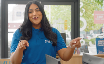 A tutor stands smiling while she explains a topic.