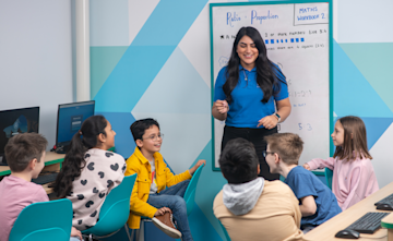 a group of children sitting round listening to a tutor.