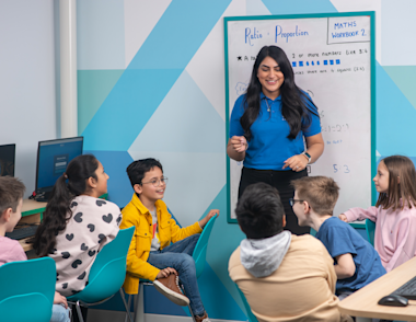 a group of children sitting round listening to a tutor.